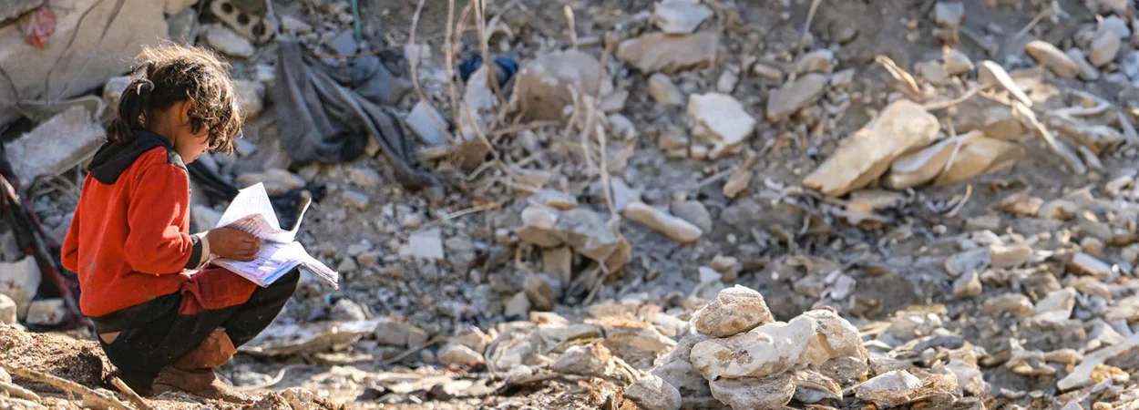 a girl reading a book in teh aftermath of earthquake in syria